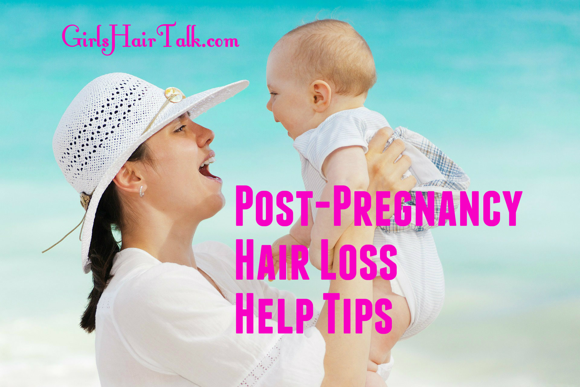 Woman wearing hat holding her cute baby in front of the blue ocean.