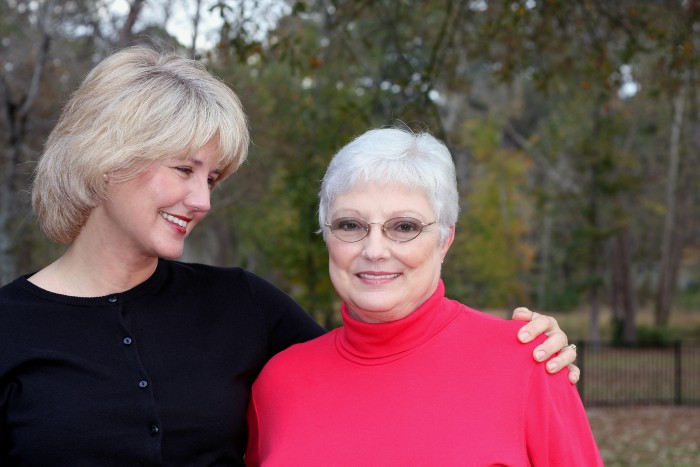 Senior mother and adult daughter hugging and smiling.